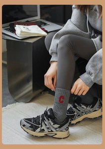 Détail de chaussettes grises avec broderie C rouge portées avec des baskets rétro