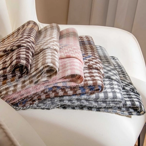 Stack of houndstooth plaid wool scarves in various colors on a white chair