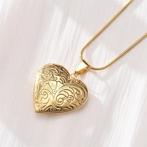 Detailed close-up of golden heart locket necklace with vintage floral engraving
