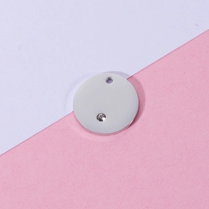 Macro shot of polished silver stainless steel round pendant with sparkling zircon accent