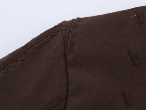 Detail of embroidered wavy stitching and cotton-blend fabric texture on dark brown top