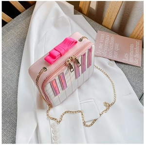Macro view of pink piano style bag with bow handle and golden chain on white blazer