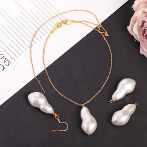 Set collana e orecchini con perle barocche dorate appoggiati su un libro d'epoca