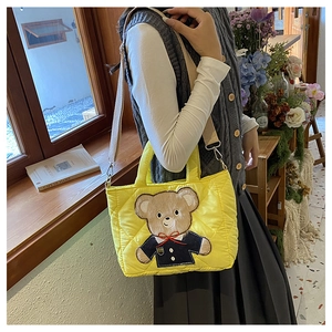 Detail of yellow quilted crossbody bag with cute bear embroidery and adjustable strap