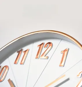 Detail shot of white wall clock dial with 3D rose gold embossed numeral scales