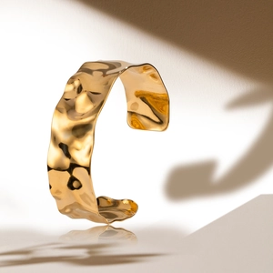 Polished wide hammer-pattern open bangle in gold finish with minimalist reflection