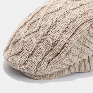 Detailed view of beige cable knit pattern and ribbed edge on a warm winter beret hat