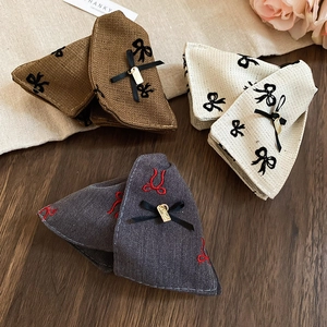Detailed embroidery and bow textures on fabric hair clips with elegant metal pendants