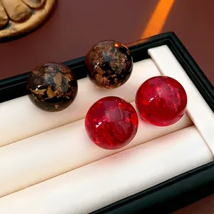 Red and amber resin stud earrings with gold foil details in a black velvet jewelry box