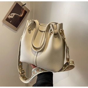Close-up of white textured leather bucket bag with woven strap and gold hardware