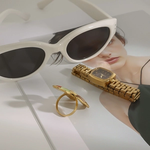 Gros plan d'une montre carrée dorée et d'une bague fleurie sur un magazine de mode