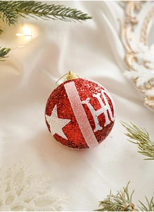 Macro detail of red Christmas ball ornament with glitter H and star on pine branches