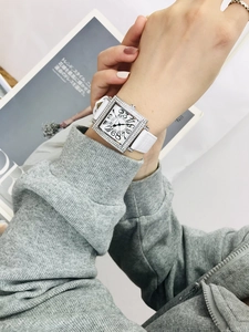 Vista detallada de un reloj cuadrado de lujo con correa de cuero blanco y bisel de cristal