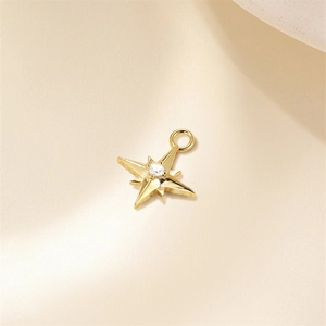 Macro detail of gold eight-pointed star charm pendant with a clear zircon stone inlay