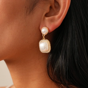 Detailed view of vintage gold drop earrings with pearls and zircon crystals worn by a model