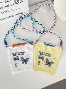 Détail de mini sacs en toile brodés avec motif papillon et bandoulières tressées