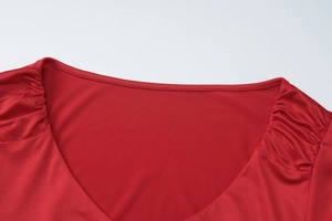 Detailed close-up of the V-neckline and pleated shoulder design on a red summer dress