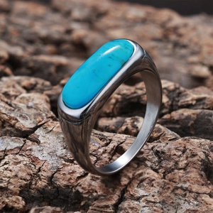 Macro shot of an oval turquoise stone set in a brushed silver ring on a bark texture