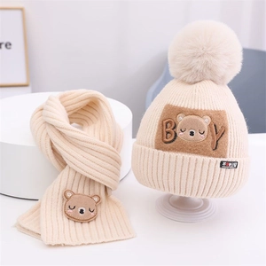 Detail der Strickstruktur von beigem Baby-Set aus Mütze und Schal mit Bären-Stickerei