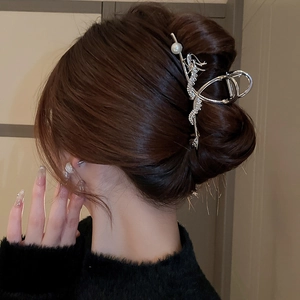 Close-up of silver dragon hair claw with pearl detail worn on a model's hair