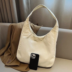Detailansicht einer beigen Cord-Hobo-Tasche auf einem Sofa mit weicher Textur und Seitenfach