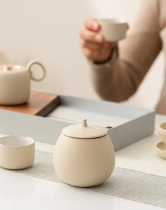 Detail of a beige spherical ceramic tea canister with matte finish in a cozy tea setting
