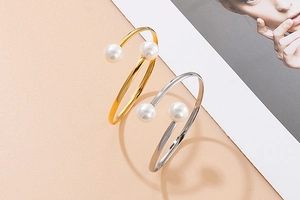 Detail of open pearl bracelets in gold and silver finish with dual white pearls