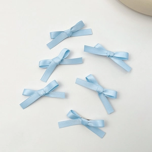 Detalle de seis pinzas para el cabello con lazos de satén azul claro en fondo blanco