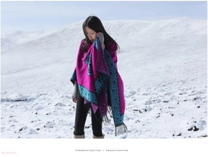 Close-up of thick ethnic cashmere shawl with magenta paisley patterns and black fringe