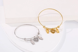 Adjustable steel coil bracelets in gold and silver with heart, boy, and girl charms