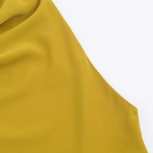Detailed macro view of ginger yellow smooth chiffon fabric with elegant silky texture draping