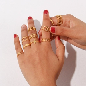 Detailed view of stacked gold woven rings and hollow mesh bands on model's hand