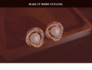 Close-up of golden double-circle earrings with central pearl and sparkling rhinestones