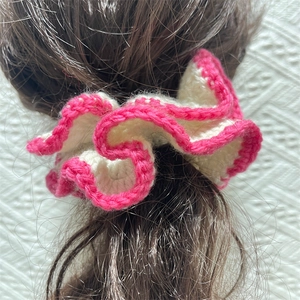 Close-up of handmade crochet ruffle hair scrunchie with pink wavy edges on dark hair
