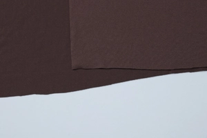 Close-up of deep brown knitted fabric texture showing premium weave and edge details