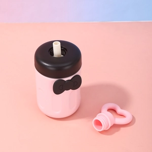 Close-up of pink stainless steel cup with black ribbon and heart straw accessory