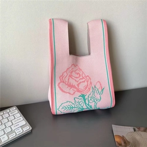 Pink knitted tote bag featuring a large rose floral pattern and green stripe accents