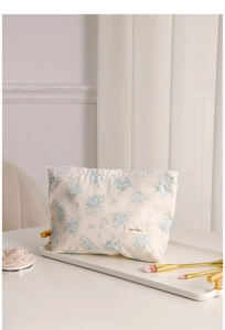 Detail view of canvas makeup bag with blue floral patterns on a white tray