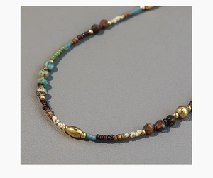 Detail of bohemian necklace with turquoise stones, wood beads and gold metallic accents