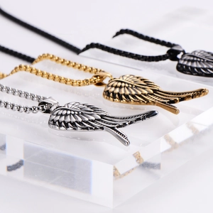 Pendentifs ailes d'ange punk rétro en argent, or et noir sur un présentoir transparent