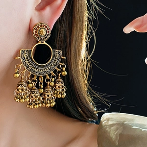 Detailed close-up of golden vintage fan-shaped earrings with traditional bell tassels