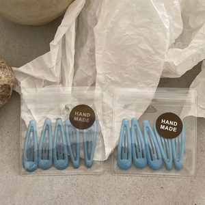 Detail of 8 pieces blue enamel drip hair clips in transparent handmade packaging