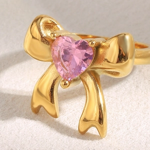 Macro shot of 18K gold bow ring featuring a pink heart-shaped zircon gemstone detail