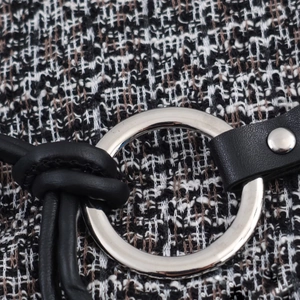Détail du tissu en tweed noir et blanc avec anneau métallique argenté et ceinture à rivets