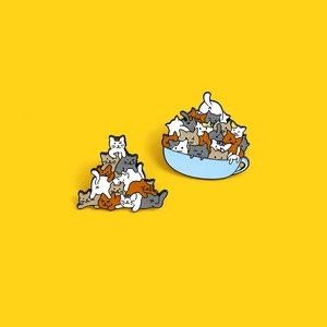 Cute stackable cat enamel pins and teacup kitten metal badges on yellow background