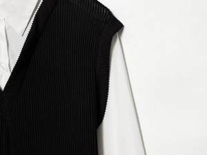Detail of V-neck knitted vest with ribbed texture over a white poplin shirt collar