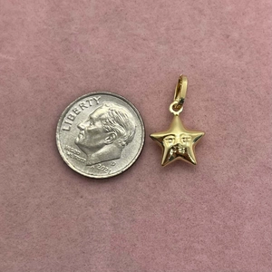 Macro shot of gold star face pendant next to a coin for size reference