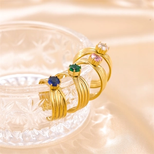Detalle de cuatro anillos dorados a capas con circonitas de colores sobre cristal