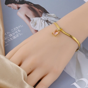 Detalle de pulsera de cadena de serpiente dorada con cristal rectangular rosa y engaste de garras