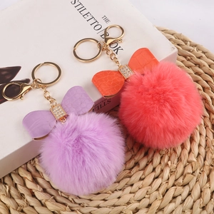 Detail of plush faux fur pompom keychains with bowknots and gold lobster clasps